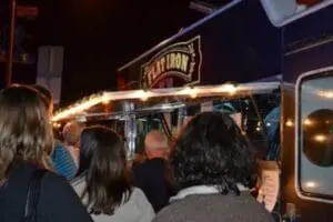 Customers queue at an illuminated food truck at night with "Eatirony" signage visible.