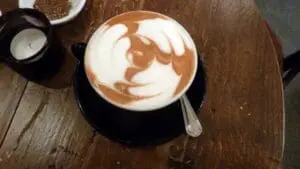 Latte with latte art in a black cup on a wooden table