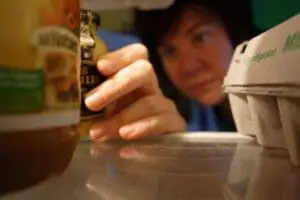 Child reaching for condiment bottle inside refrigerator