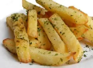 Crispy golden French fries seasoned with herbs on a white plate
