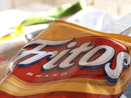 Frito-Lay chip bag package displayed on white surface with green onion in background