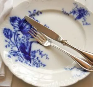 Blue and white decorative plate with fork and knife placed on it
