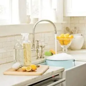 Clean kitchen sink with lemons, cleaning supplies, and light natural decor