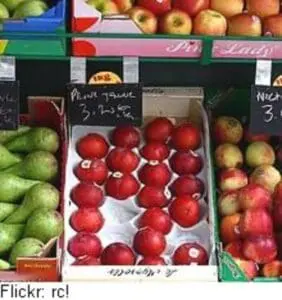 Red apples and other fresh produce displayed at a farmers market stand