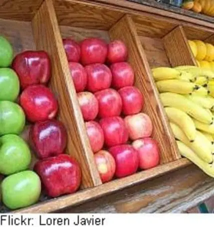 Wooden crates of fresh green apples, red apples, and yellow bananas at a fruit stand