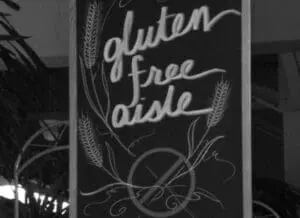 Chalkboard sign advertising gluten free aisle with wheat illustrations