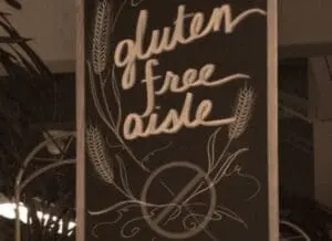 Chalkboard sign with "gluten free aisle" text and wheat stalk illustrations