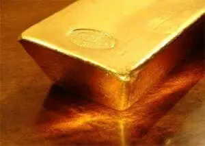 Gold ingot casting a shadow on wooden surface