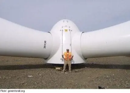 Worker standing in front of a wind turbine nacelle during installation