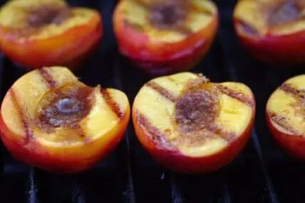 Grilled peach halves with caramelized edges on a barbecue grate