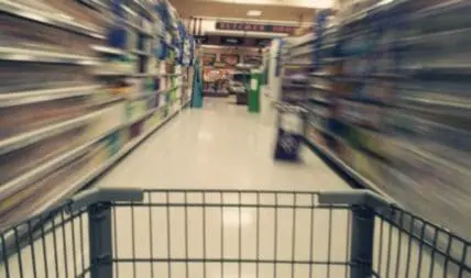 Shopping cart moving through a supermarket aisle with blurred shelves on both sides