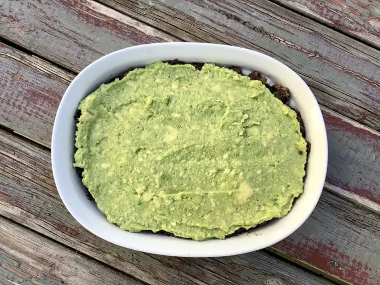 image of an overhead shot of guacamole as the third layer of a healthy vegan black bean layer dip