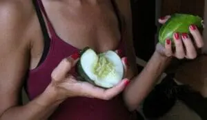 Woman holding halved cucumber with manicured nails for beauty demonstration