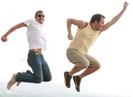 Two men jumping in the air with joyful expressions against a white background