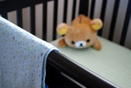 Baby crib with stuffed animal and patterned crib sheet