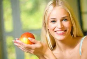 Smiling woman holding a fresh red apple