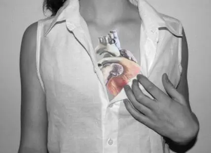Woman in white shirt holding a transparent illustration of a human heart over her chest