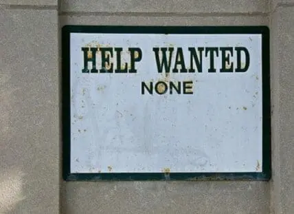 Weathered "Help Wanted None" sign on concrete wall