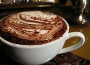Cup of hot chocolate with cocoa powder and decorative swirl design