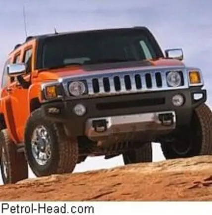 Orange Hummer H2 SUV parked on sandy terrain against cloudy sky