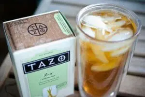 Tazo Zen iced tea box next to a glass of iced tea with ice cubes