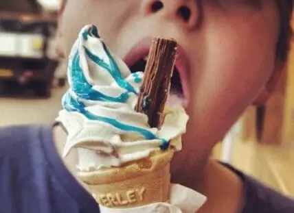 Child eating soft serve ice cream with chocolate flake