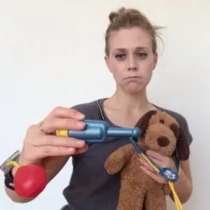 Woman holding stethoscope and toy bear with sick expression