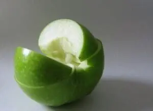A green apple cut in half, revealing the pale flesh inside