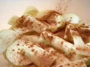 Sliced apples dusted with cinnamon on a white plate