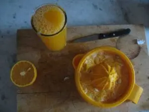Fresh orange juice and sliced oranges on a wooden cutting board