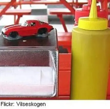 Toy car and condiment bottle on red and white fast food tray