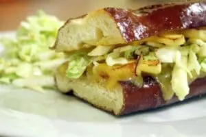 Cheddar cheese sandwich on pretzel bread with apple and cabbage slaw