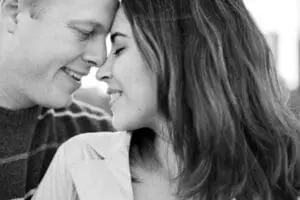 A couple touching foreheads and smiling in a close, intimate moment.
