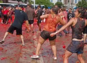 Participants throwing tomatoes and playing in red pulp at La Tomatina festival