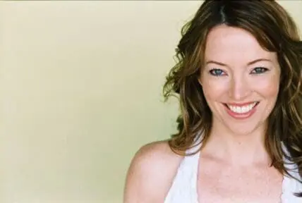 Woman smiling at camera against neutral background