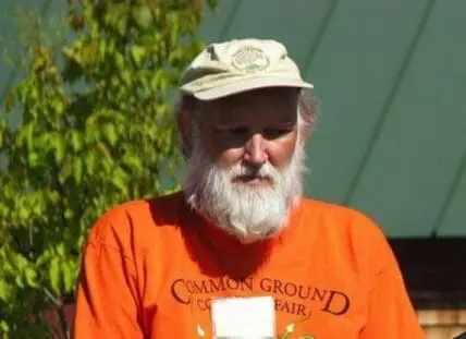 Russell Libby wearing an orange Common Ground Fair shirt and tan cap