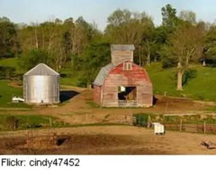 Red barn with metal grain silo on rural farm with fenced pasture