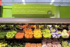 Grocery store produce section with locally grown vegetables display and signage