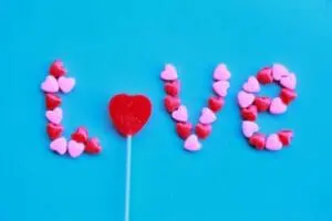 The word "LOVE" spelled out with red and pink heart-shaped candies on a blue background