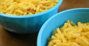 Two blue bowls of mac and cheese on a brown surface
