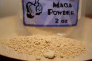 Maca powder spilled from a labeled container onto a wooden surface