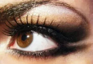 Close-up of an eye with golden eyeshadow and black mascara applied to upper lashes