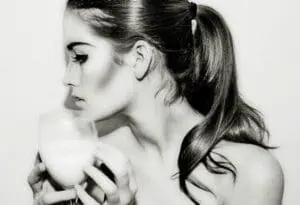 Woman holding a cup of liquid near her face in profile