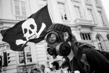 Protester wearing gas mask holds Jolly Roger flag at demonstration against Monsanto