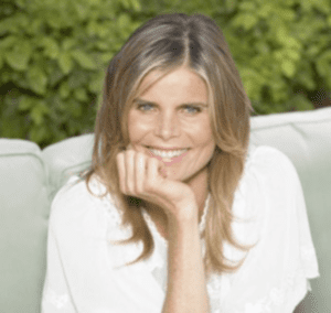 Mariel Hemingway smiling at the camera in a white shirt outdoors