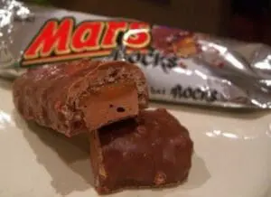 Cross-section of a Mars chocolate bar showing nougat and caramel layers with wrapper in background