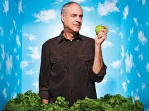 Mark Bittman holding a green apple with lettuce in the foreground