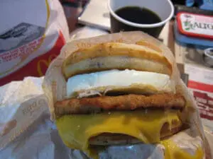 Stacked breakfast sandwich with egg, sausage patty, cheese, and buttered bun