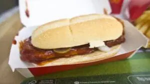 McDonald's McRib sandwich on a wrapper-lined tray with fries visible in background