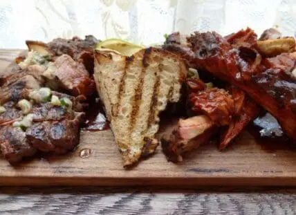 Assorted grilled and roasted red meat cuts on a wooden serving board